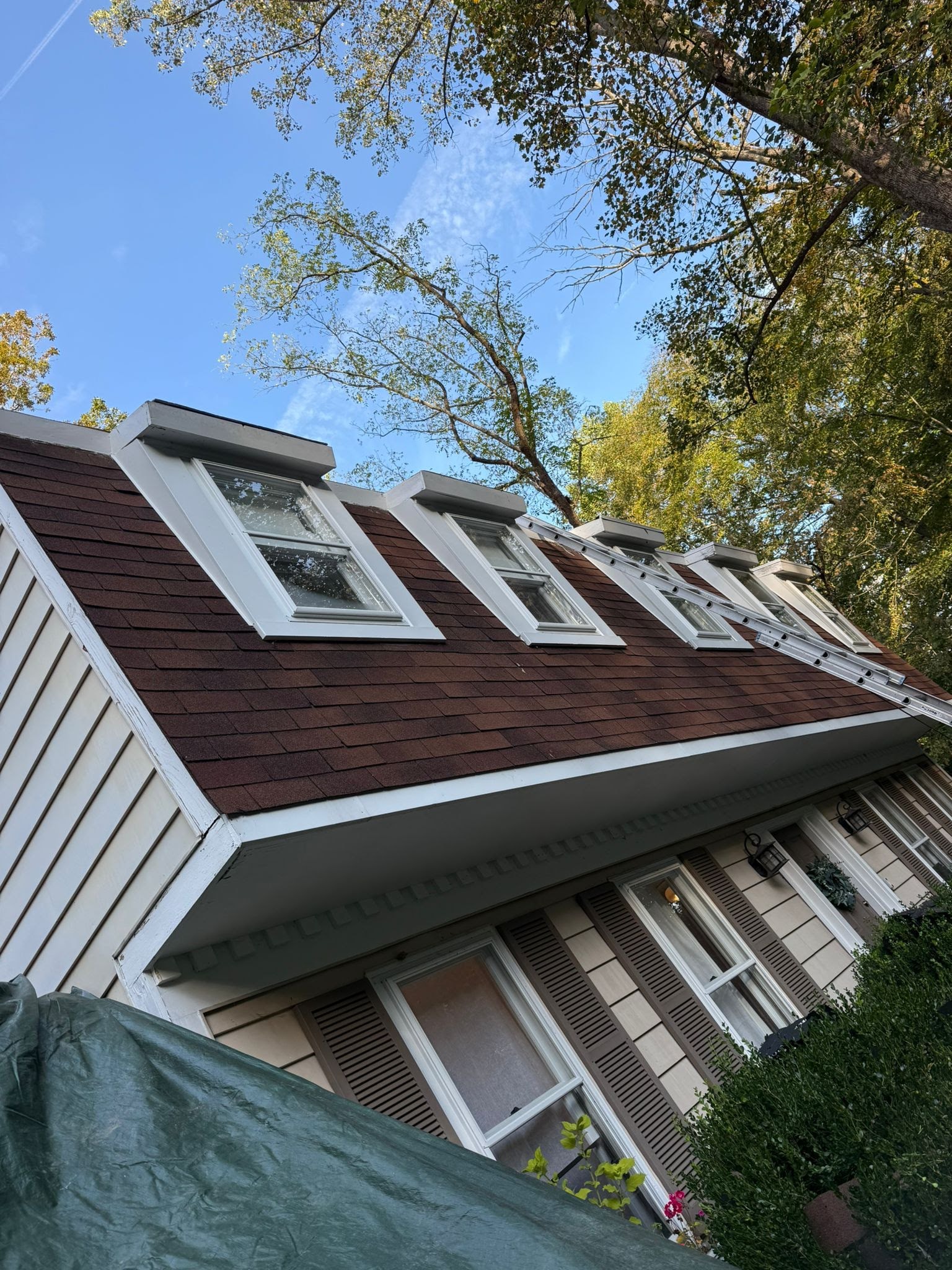 Home during roof tear-off with decking exposed and crew on site