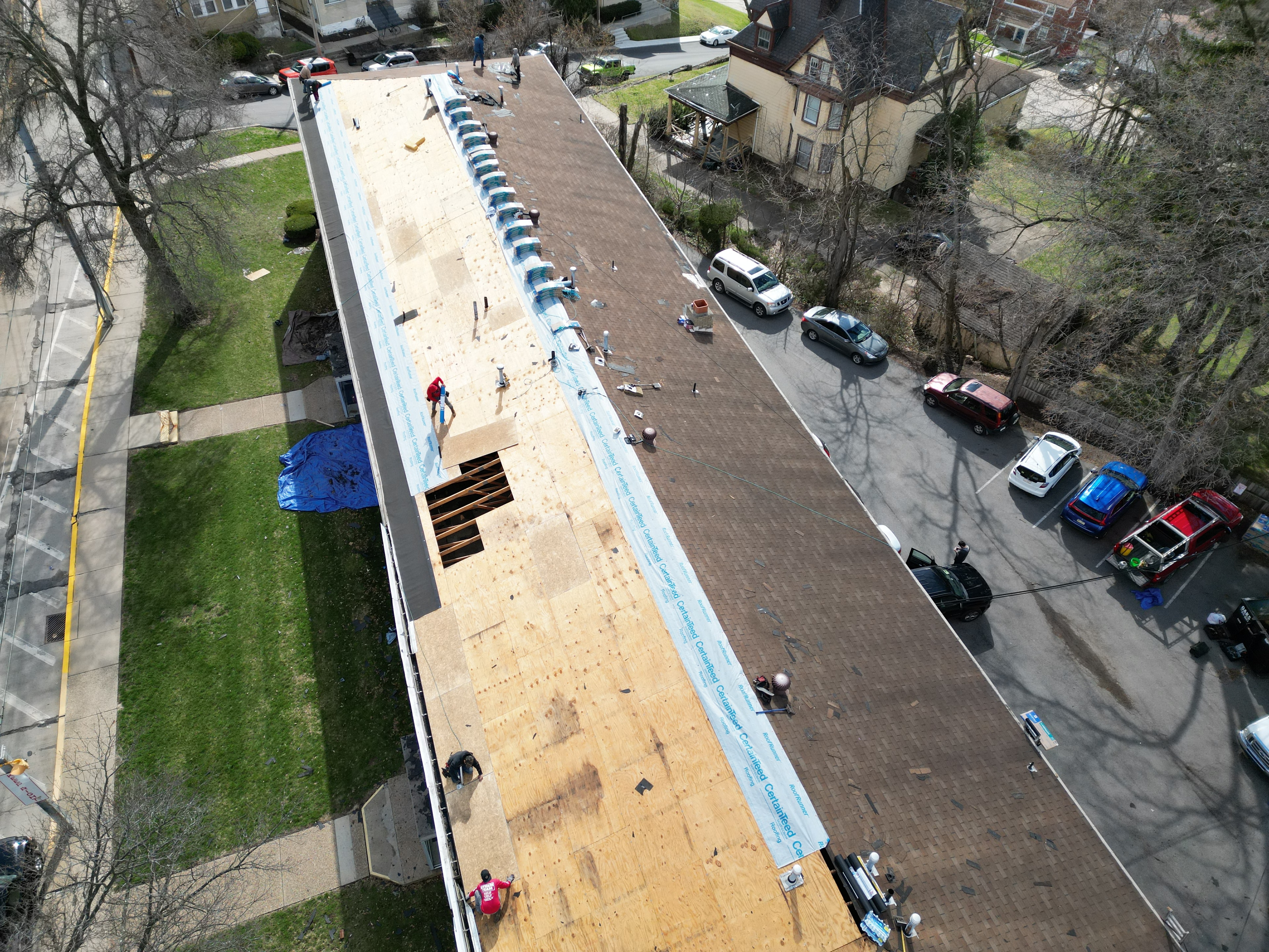 Aerial view of roof tear-off with new plywood decking being installed